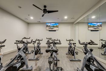 a room filled with spin bikes and a ceiling fan